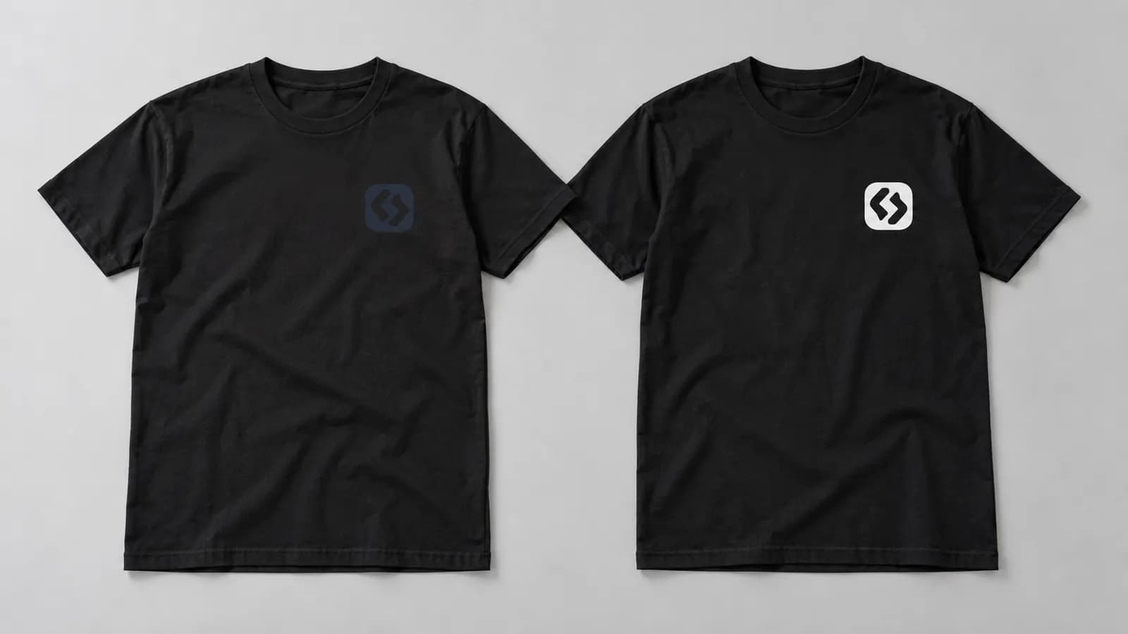 Two black T-shirts: one with a dark, barely visible logo and one with a light, clearly legible logo